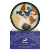 A hop hare crystal magic flower candle with white wax, dried orange and blue leaves, citrine and sodalite stones in green glass