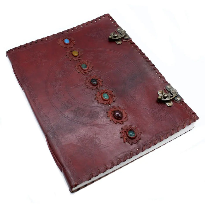 A huge burgundy leather book with six colorful chakra gemstones set in floral designs and secured by metal clasps