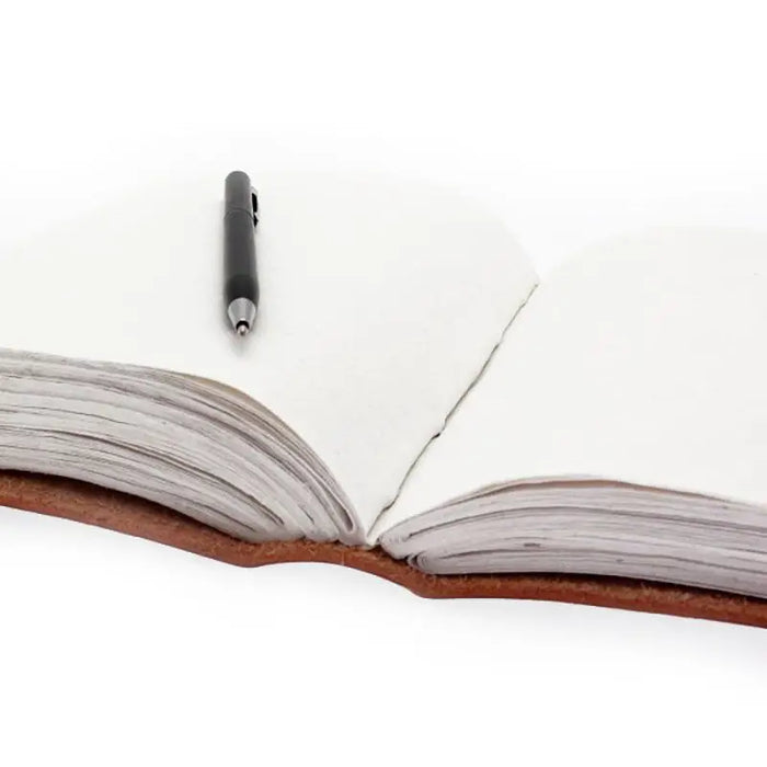 A brown leather bound huge leather book 7 chakras with metal clasps and a black pen with a silver tip on its pages