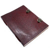 A huge burgundy leather book with an embossed flower of life pattern and ornate metal clasps measures 13 by 10 inches