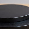 Black circular coaster with smooth matte finish and raised edge on ian snow dark wood cheese board