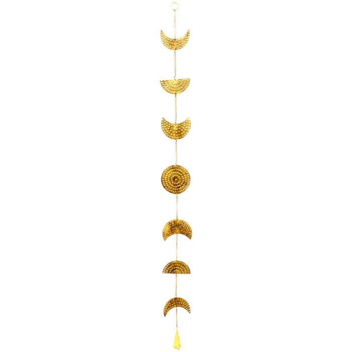 Golden brass moon phase wall hanging with textured hammered surfaces and a yellow tassel at the bottom with a bell