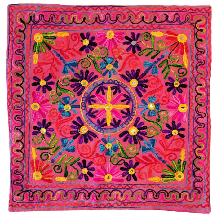 Vibrant pink embroidered cushion cover with bold purple blue and yellow floral patterns and a central golden cross motif