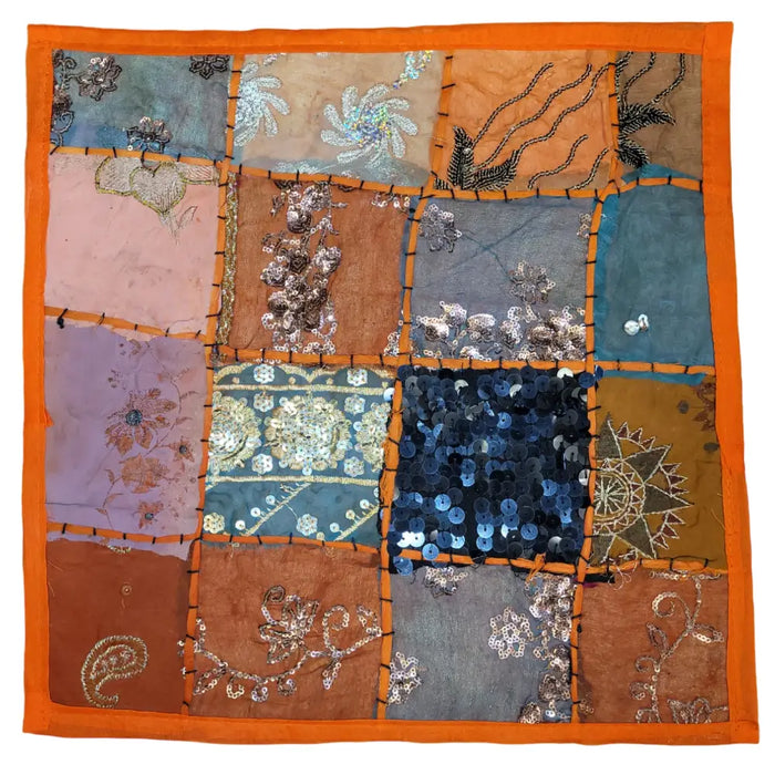 A vibrant indian patchwork cushion cover with orange border featuring colorful embroidered and sequined fabric squares