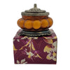 Amber-colored segmented glass jar incense burner with ornate silver-toned lid and base in antique style patchouli amber design