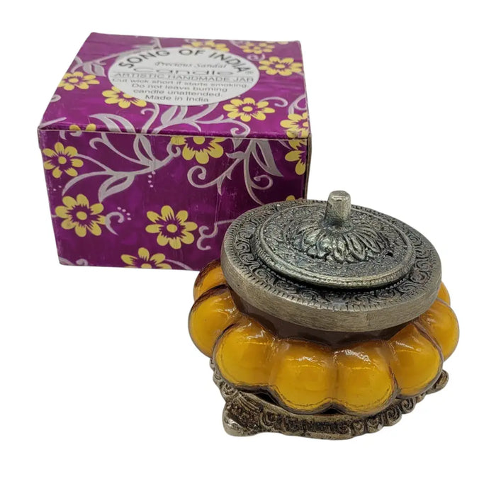 Ornate silver-toned lid with floral engraving on an amber glass jar candle in antique style with precious sandal scent