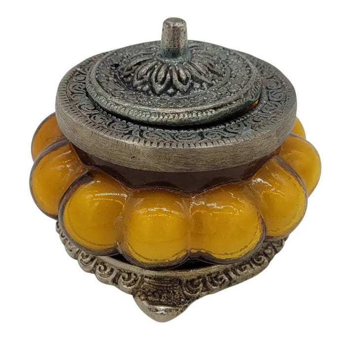 Ornate silver toned metal incense burner with amber glass segments in an antique style glass jar for precious sandal scent
