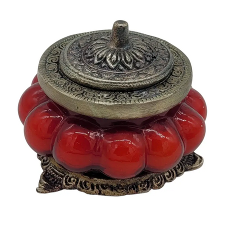 Red glossy ceramic incense burner with ornate white metal lid and base in antique style glass jar with floral patterns