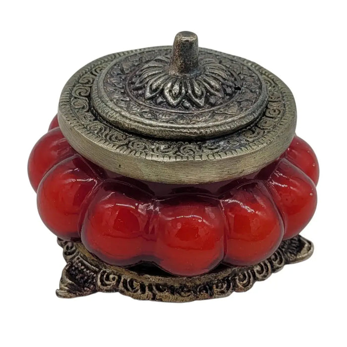 Red glossy ceramic incense burner with ornate white metal lid and base in antique style glass jar with floral patterns