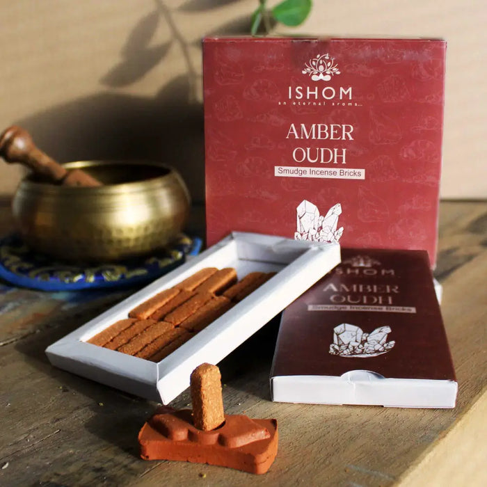 A single amber oudh incense smudge brick standing upright in a terracotta ceramic holder for smudge bricks use