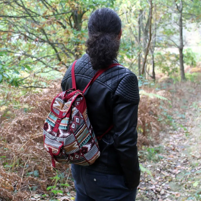 A jacquard backpack in chocolate with red drawstring straps and an earthy geometric pattern