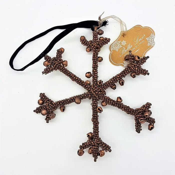 A copper-colored beaded snowflake hanging decoration with small bells and a black ribbon for hanging