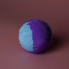 A jumbo bath bomb called amethyst creed with a vibrant purple and blue split design made with sodium lauryl sulfoacetate