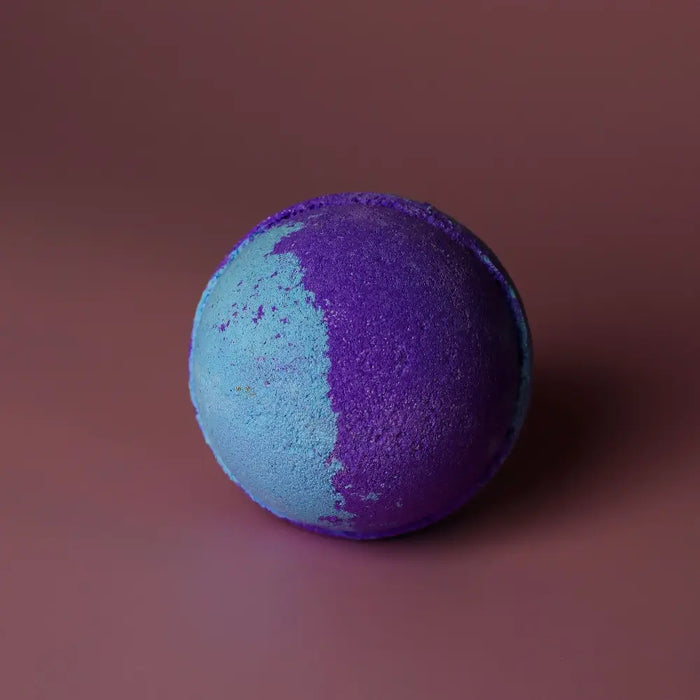 A jumbo bath bomb called amethyst creed with a vibrant purple and blue split design made with sodium lauryl sulfoacetate