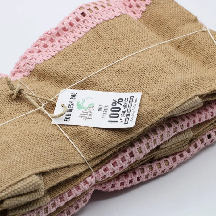 Tan burlap jute and cotton mesh bag with pink crocheted trim shown on a plain background