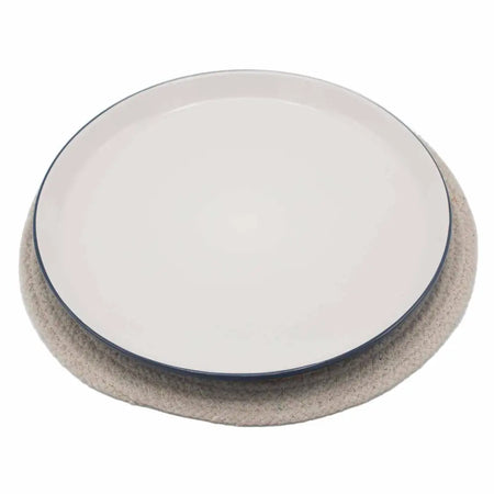 A minimalist white ceramic plate with a navy blue rim on an ivory jute and cotton woven placemat