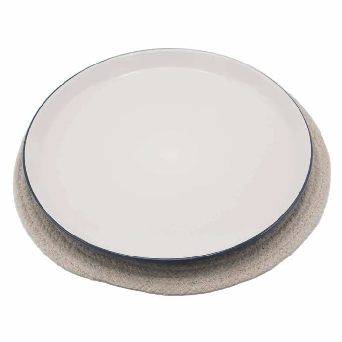 A minimalist white ceramic plate with a navy blue rim on an ivory jute and cotton woven placemat