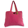 A vibrant pink jute and cotton tote bag with tan straps and a front pocket with a dark wooden button