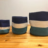 Three handwoven jute rope storage baskets in navy cream and teal stripes with evil eye design for rope storage use