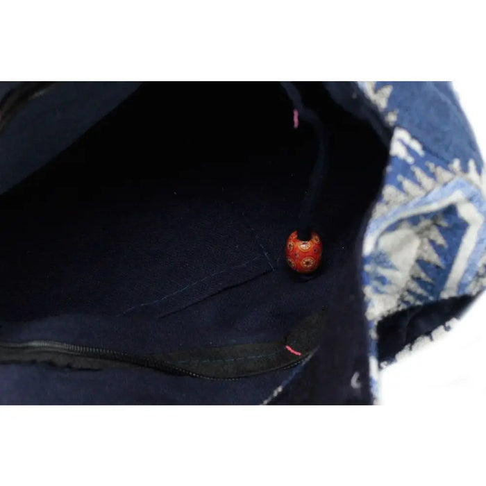 A small round orange bead with gold patterns inside a dark blue fabric bag in the kathmandu big dusk bag