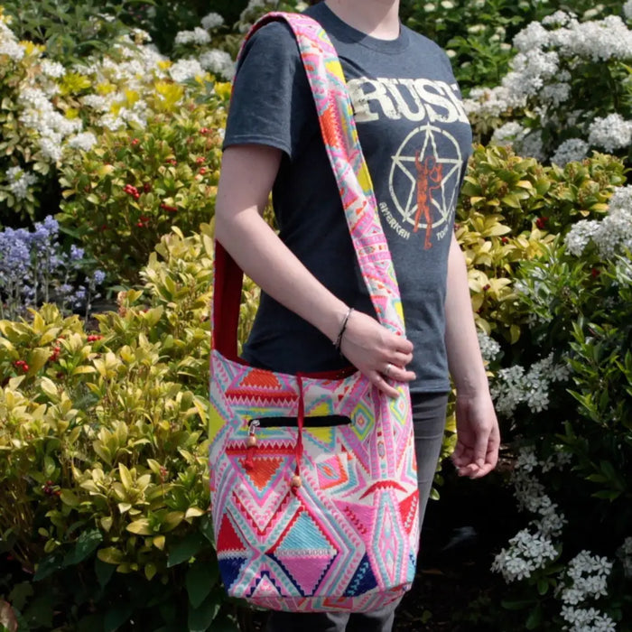 Kathmandu big bag sunrise crossbody bag with vibrant pink red and blue geometric patterns and a solid red strap