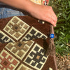 Brown kilim summer messenger bag with geometric patterns in beige black rust and a blue beaded tassel accent