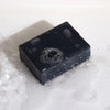 A sleek black rectangular bar of Klay soap with activated charcoal and fuller’s earth bubbles on its glossy surface