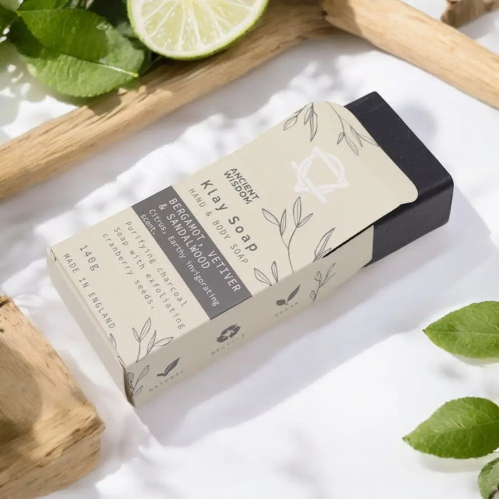 A rectangular beige and black box of ancient wisdom klay soap with fuller s earth and activated charcoal illustrations