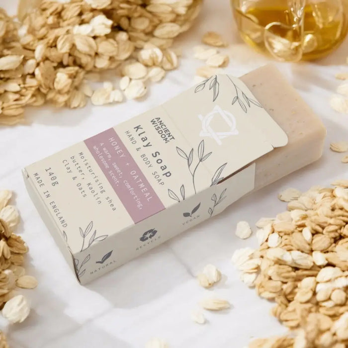 A rectangular pale beige kaolin clay soap bar wrapped in white and mauve paper with leafy line art packaging