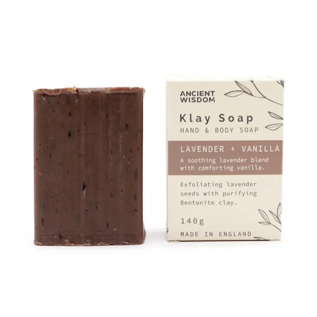 A rectangular dark brown klay soap bar with speckles next to its lavender vanilla packaging featuring lavandula angustifolia