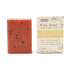 A rectangular orange klay soap bar with black speckles in a cream box labeled ancient wisdom with peel oil and coffee grounds