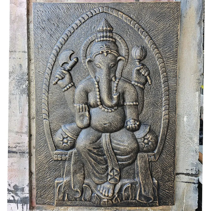 Dark gray textured concrete large antique gold ganesha relief depicting ganesha seated within an arched frame