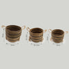 Set of three woven banana leaf and seagrass baskets in natural brown tones with dark stripes, tassels, and handles