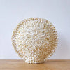 A round 30cm off-white shell lamp made from small cylindrical shells in a boho cut art floral design