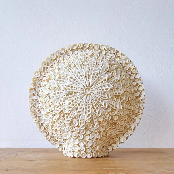 A round 30cm off-white shell lamp made from small cylindrical shells in a boho cut art floral design