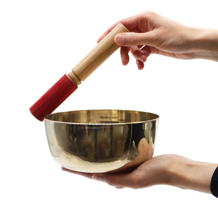Large brass singing bowl in shiny gold tone with wooden mallet featuring red rubberized handle for singing bowls use