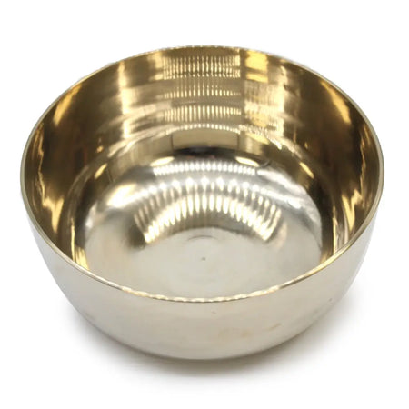 A large brass singing bowl with a polished reflective interior and subtle horizontal ridges on the exterior