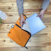 Large canvas laptop pouch in orange with black zipper and trim made from durable material with small brand logo on corner