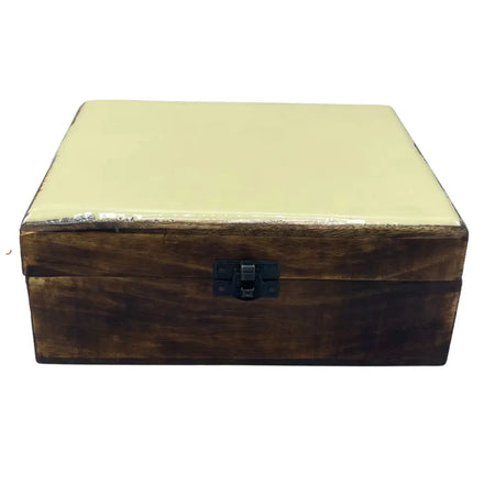A large ceramic glazed wooden box with a smooth pale yellow lid and dark brown sides in a concrete setting