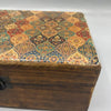 A large ceramic glazed wooden box with a patterned lid in warm red gold teal and brown tones