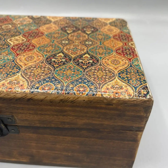 A large ceramic glazed wooden box with a patterned lid in warm red gold teal and brown tones