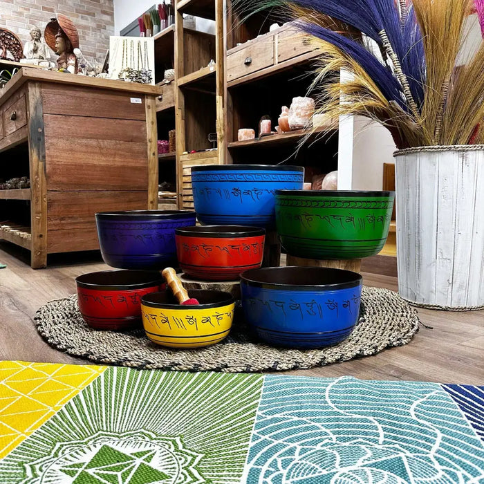 Large chakra set of seven singing bowls in blue green red and yellow with engraved sanskrit mantras on metal rims