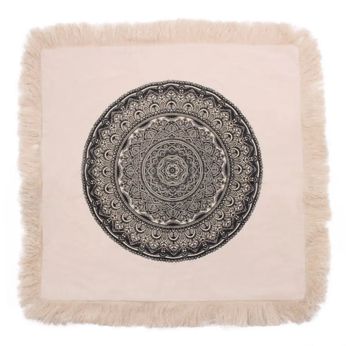 A beige cotton cushion cover 60cm with a black mandala design and fringed edges in a square shape