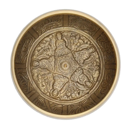 A large brass singing bowl with intricate engravings of five buddha figures and ornate patterns