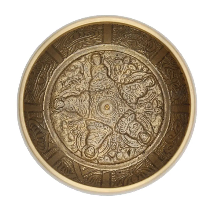 A large brass singing bowl with intricate engravings of five buddha figures and ornate patterns