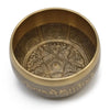A large brass five buddha singing bowl with intricate engraved designs and sanskrit script along the rim