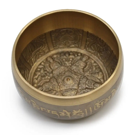 A large brass five buddha singing bowl with intricate engraved designs and sanskrit script along the rim