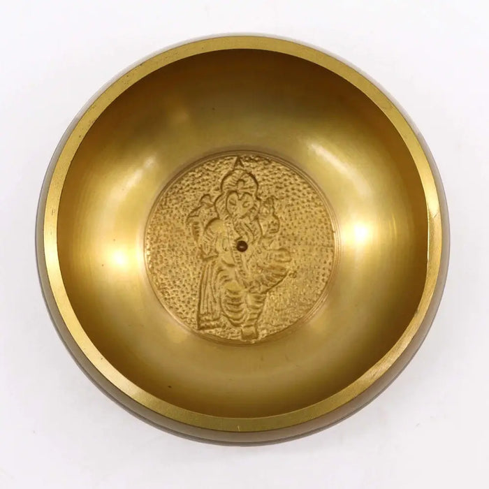 Large golden brass singing bowl with embossed ganesh deity at center for meditation and sound healing