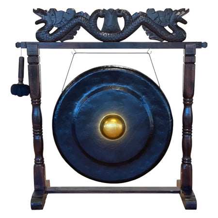 Large dark blue gong with golden center on an antique brown wooden stand featuring carved dragon heads
