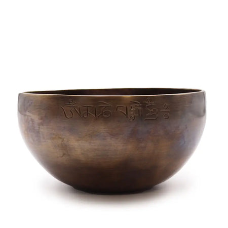 A large indian moon phase singing bowl made of hand-forged bronze with engraved sanskrit script on the rim